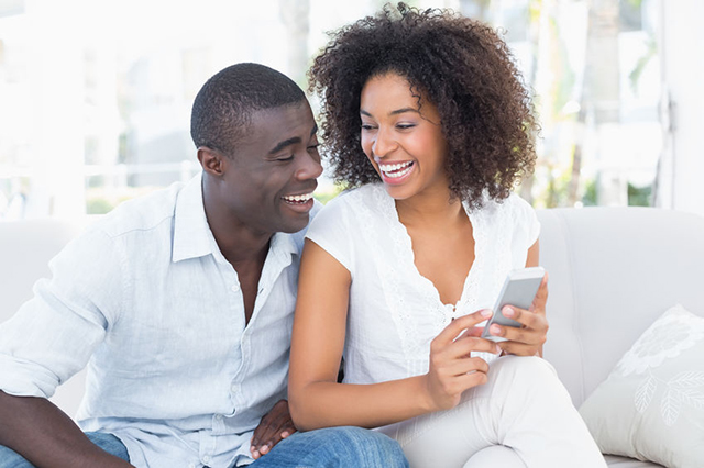 Man and woman laughing together on settee